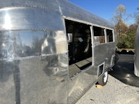 a silver airstream trailer is parked in a gravel lot