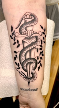 a black and white tattoo of a snake on a person's forearm