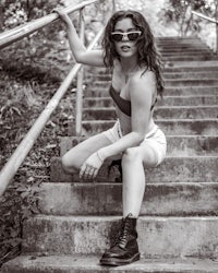 a woman in a bikini sitting on a set of stairs