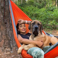 a woman sitting in a hammock with her dog