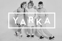 a black and white photo of three children posing in front of the word yarka