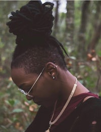 a woman with dreadlocks standing in the woods