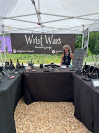 a woman standing in front of a tent with a table full of jewelry