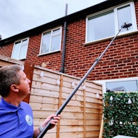 Man cleaning windows at a house in Maghull, Merseyside