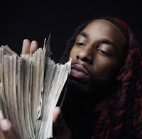 a man with dreadlocks holding a stack of money