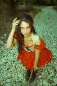 a girl in a red dress posing on a gravel path