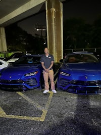 a man standing next to two blue lamborghinis