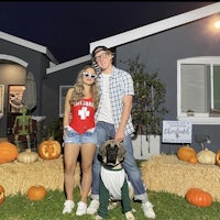 a couple dressed up for halloween in front of a house with a dog