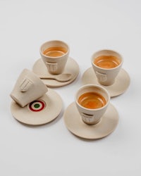 four coffee cups and saucers on a white surface