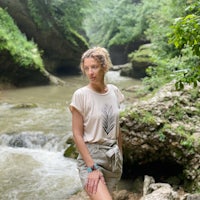 a woman in a t - shirt standing near a river