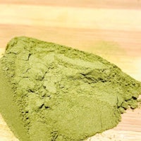 a pile of green powder on a wooden table