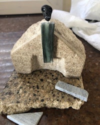 a model of a house with a stone on top of it