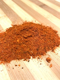 a pile of red chili powder on a wooden table