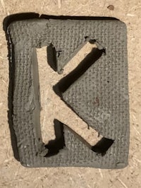 the letter k is cut out of a piece of concrete