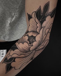 a black and white flower tattoo on a woman's arm