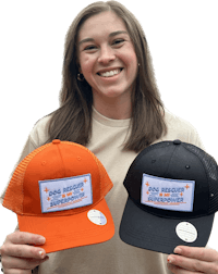a woman is holding an orange and black trucker hat