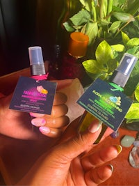 two hands holding two bottles of essential oils