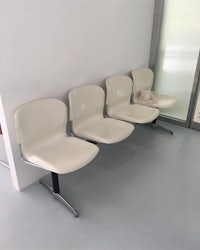 a row of white chairs in a waiting room