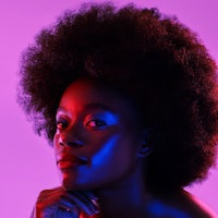 a black woman with an afro posing in front of a purple background