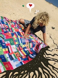 a child playing with a flag blanket on the sand