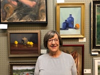 a woman standing in front of a wall full of paintings