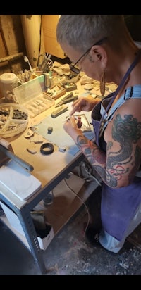 a woman working at a table with a tattoo on her arm