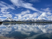 the grand teton mountains are reflected in a lake