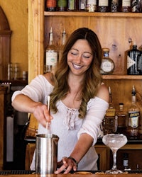 a woman preparing a cocktail at a bar