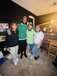 four people posing for a picture in a living room
