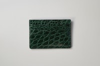 a green crocodile card holder on a white surface