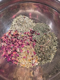 a bowl of dried herbs and flowers on a table