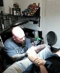 a man is getting his arm tattooed by a tattoo artist