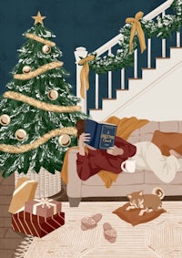 a woman is reading a book on the couch next to a christmas tree