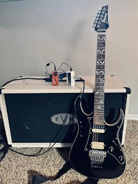 a black electric guitar sitting next to a guitar amp