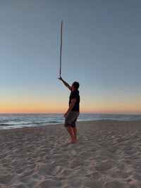 a man standing on the beach with a kite in his hand