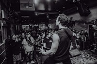 a black and white photo of a man playing a guitar in front of a crowd