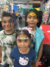 three children posing for a picture with face paint