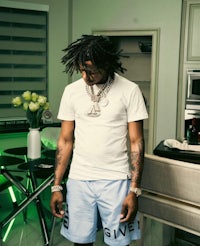 a man with dreadlocks standing in a kitchen