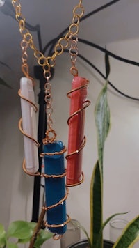 a blue, red, and green spiral necklace hanging from a plant