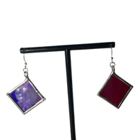 a pair of earrings with purple and blue squares on a black stand