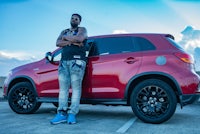 a man standing next to a red suv