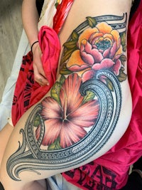 a woman's thigh tattooed with hibiscus and flowers