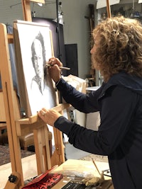 a woman drawing a fish on an easel