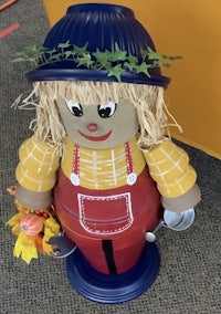 a scarecrow with a hat and leaves on his head