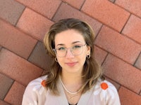 a woman wearing glasses is leaning against a brick wall