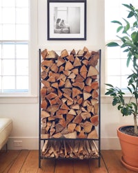 a firewood rack in a living room with a potted plant