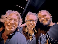 three men posing for a selfie in a dark room