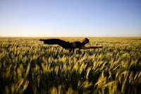 a woman doing yoga in a field of wheat