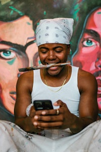 a man holding a cell phone in front of a mural
